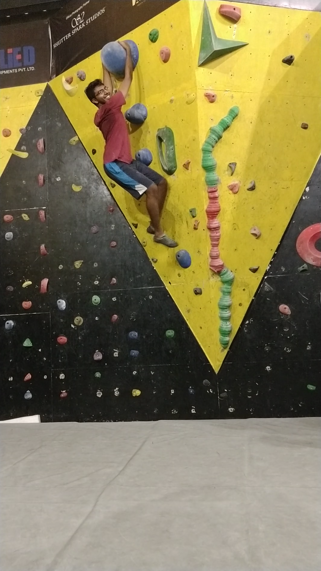 Bhishma midway through an indoor climbing route